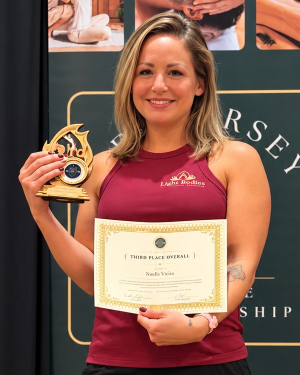 Noelle Vieira holding her third place overall trophy and certificate at the 2026 New Jersey Massage Championship
